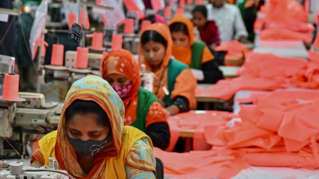 Workers operating sewing machines in a garment factory production line in Bangladesh textile industry